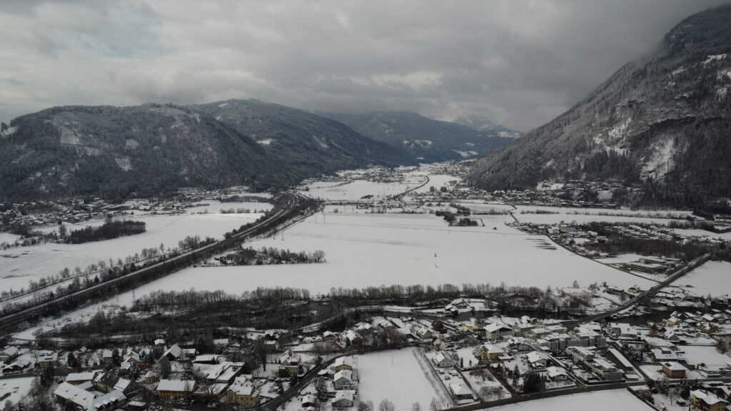 A picture of a snow covered valley between two mountains which was shot on a drone while flying during winter times.